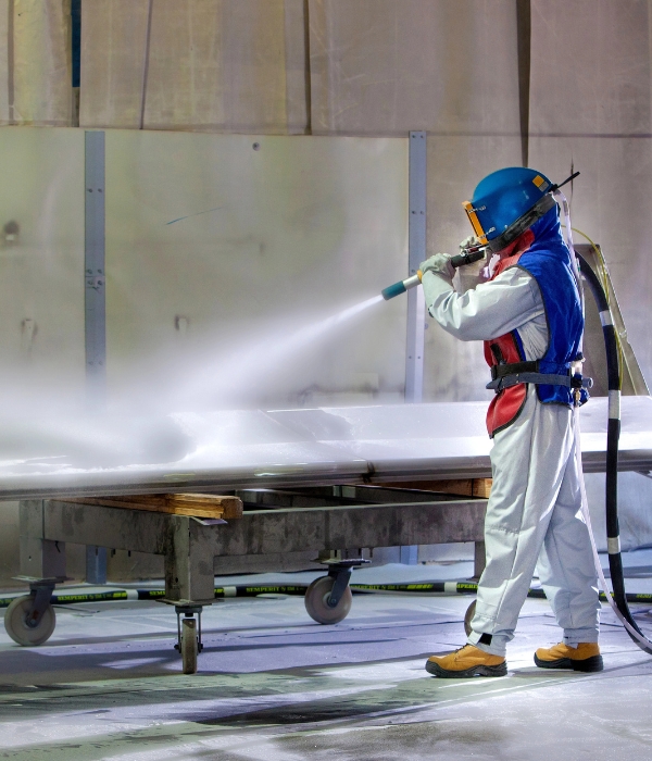 Person sandblasting a large piece of metal